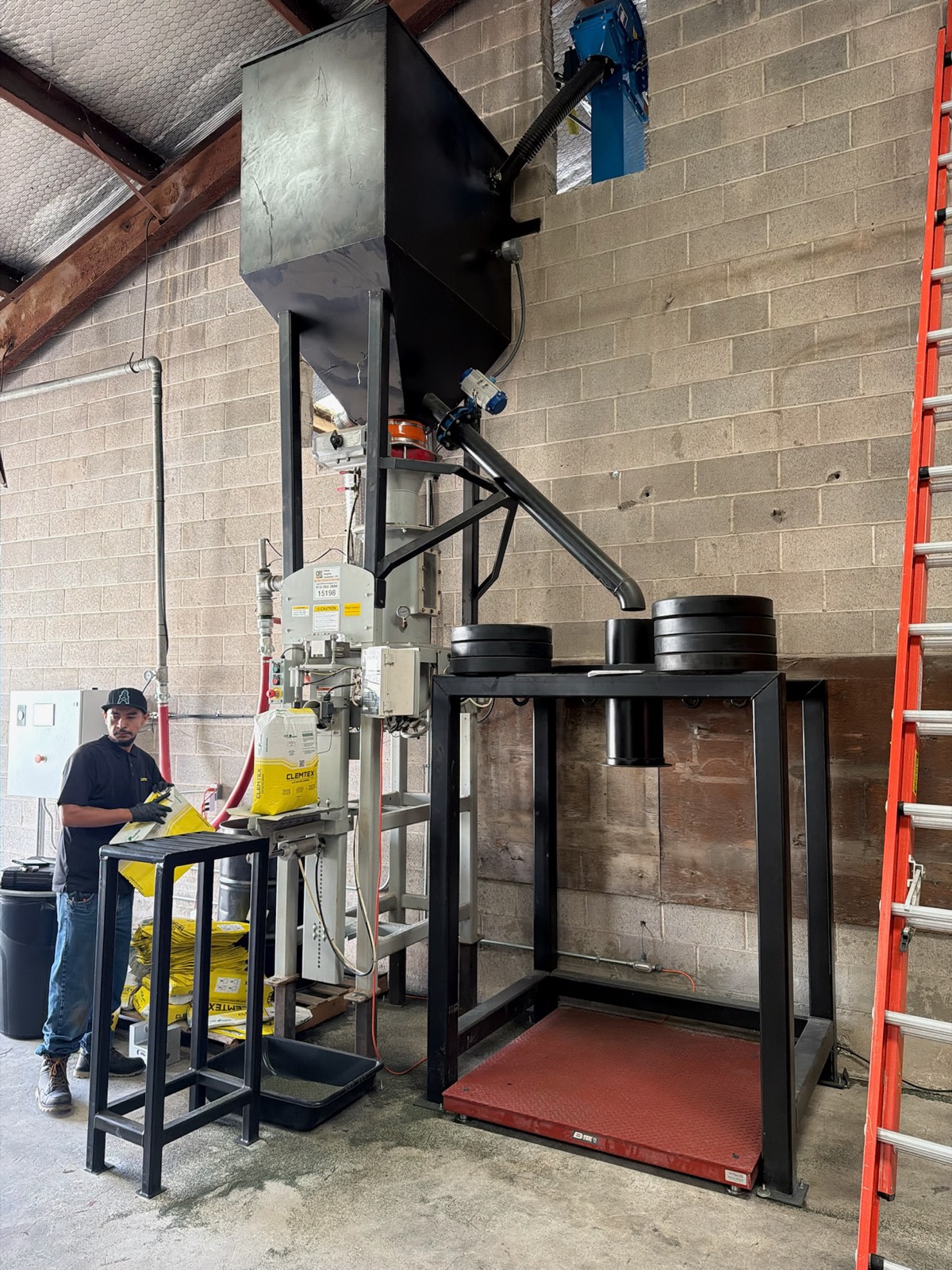 Bag fill station under a weigh hopper with a platform scale and test weights
