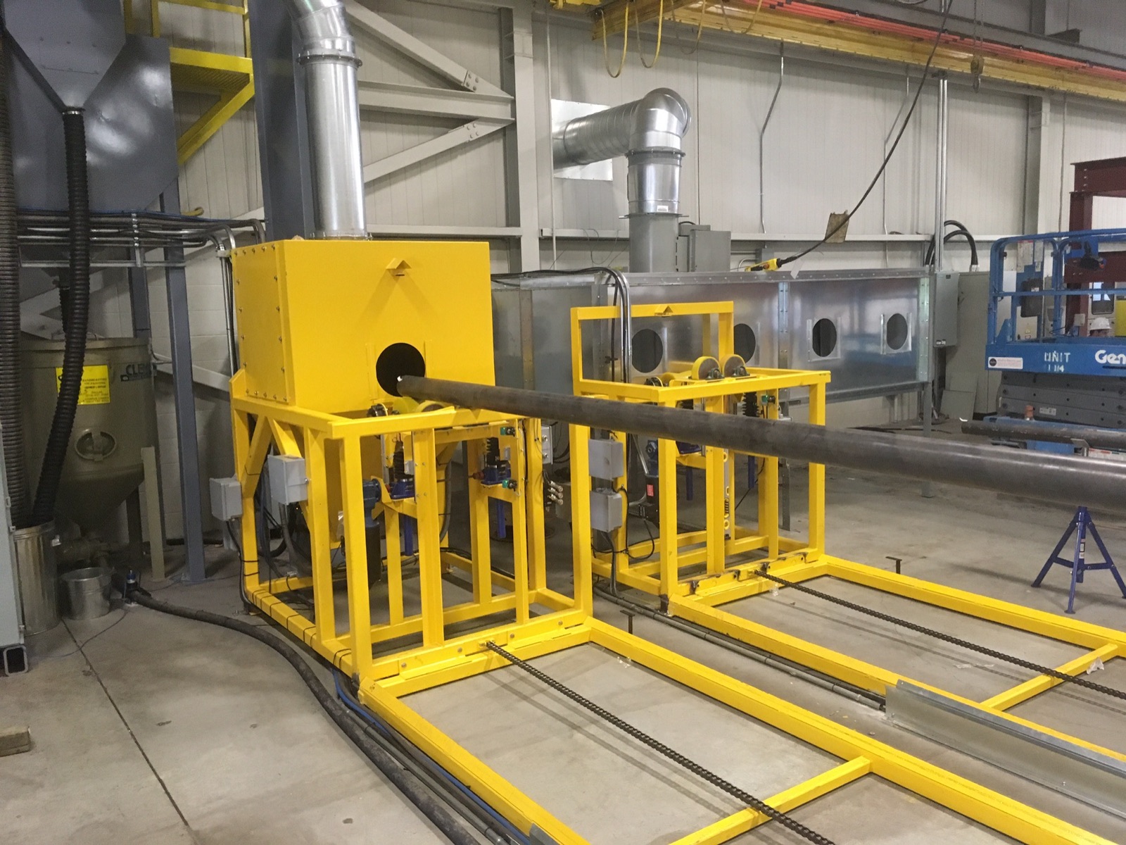 Pipe blast station with a tube on the rotation wheels and the blast cabinet behind