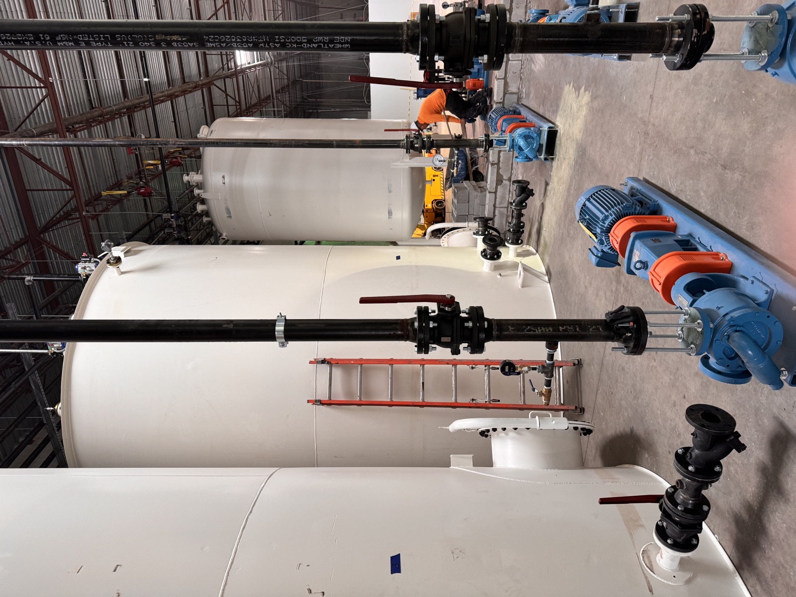 Storage tanks with transfer pumps and isolation valves in the foreground