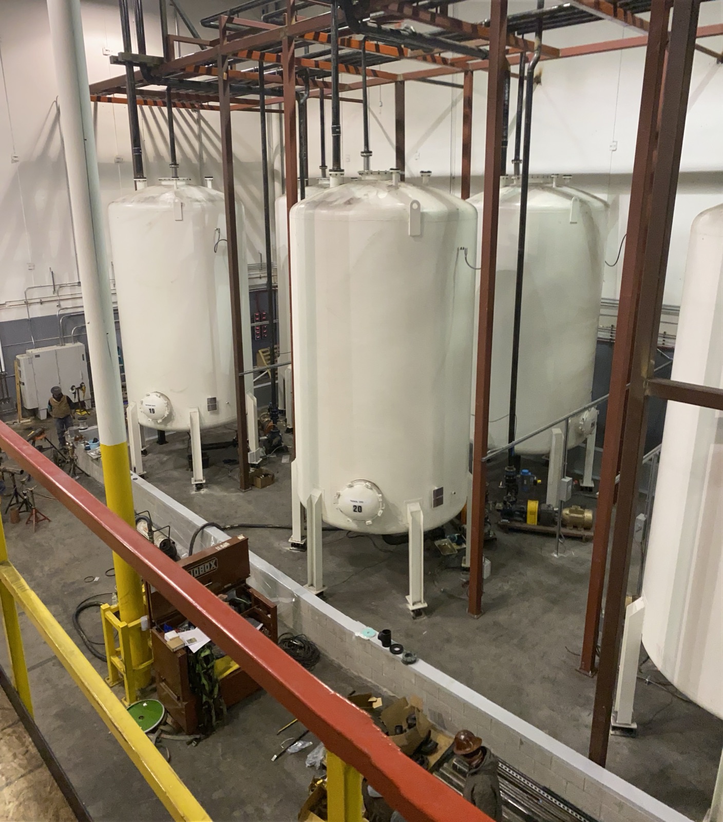 Indoor tank farm with storage tanks and overhead piping